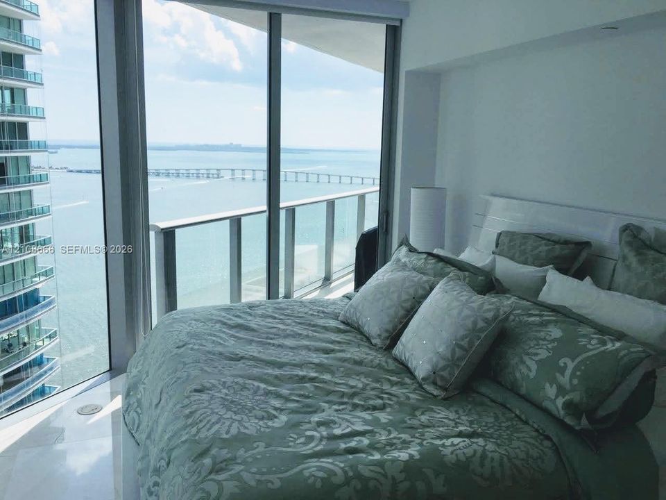Floor-to-ceiling windows, attached glass-railed balcony, and polished stone flooring