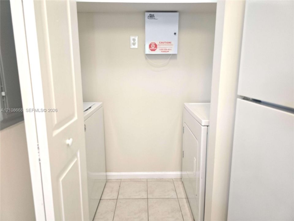 Utility closet featuring tiled flooring, bi-fold doors, and a wall-mounted security panel