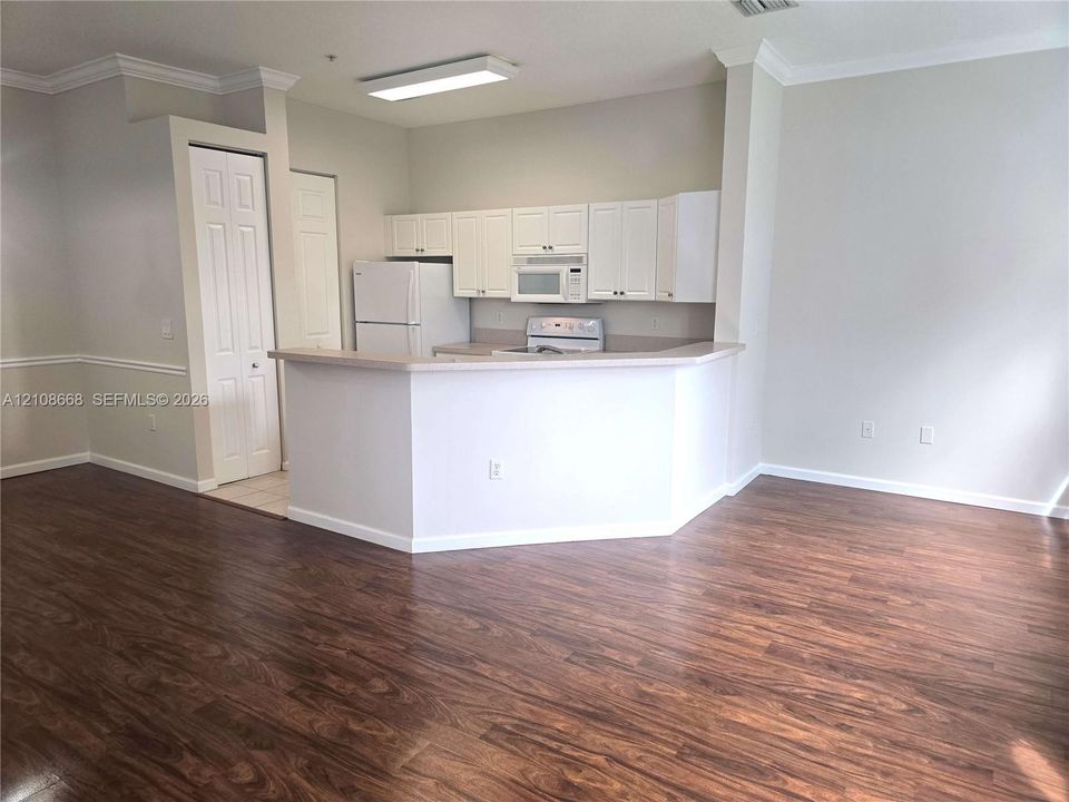 Kitchen featuring white cabinetry, wood-finish flooring, a breakfast bar, and neutral wall tones