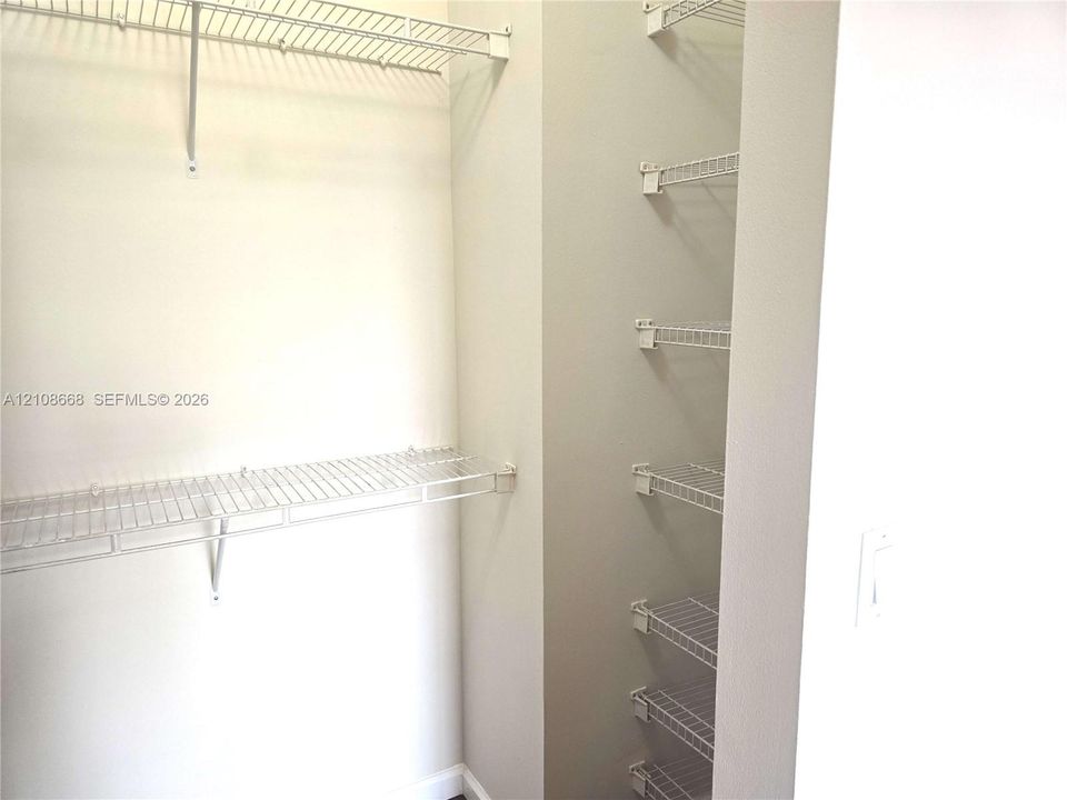 Storage area featuring white wire shelving units and wall-mounted racks