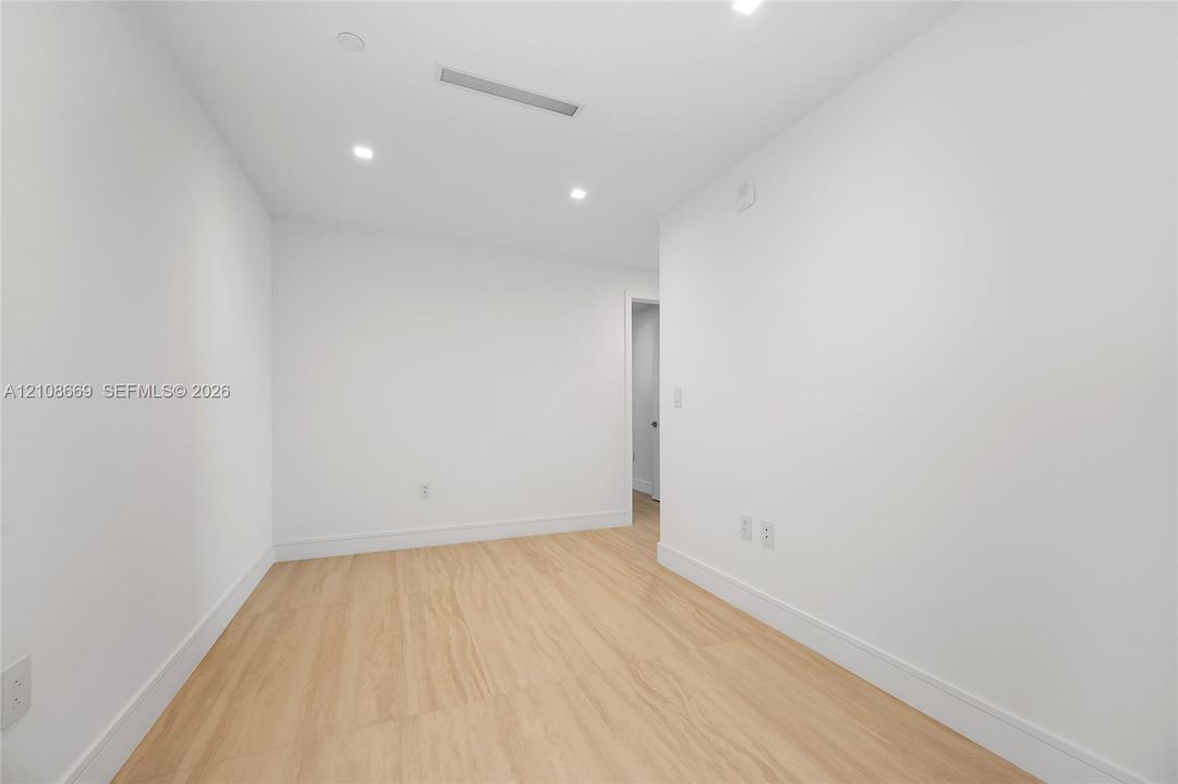 Neutral-toned room featuring recessed ceiling lighting and wood-finish flooring