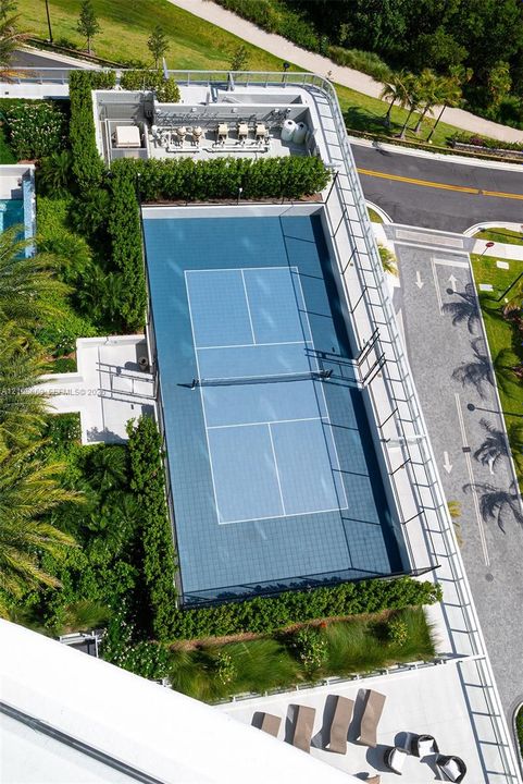 Tennis court featuring a blue hard-surface finish, perimeter fencing, and professional-grade net