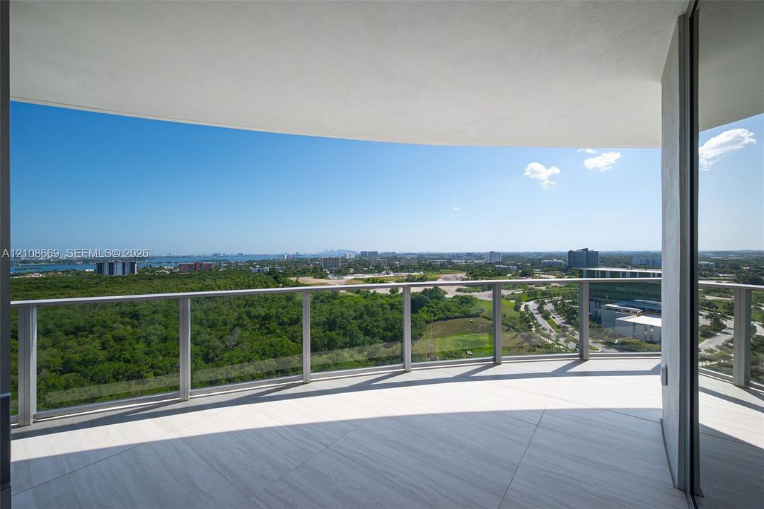Covered balcony featuring oversized stone-finish flooring and a glass-paneled metal railing