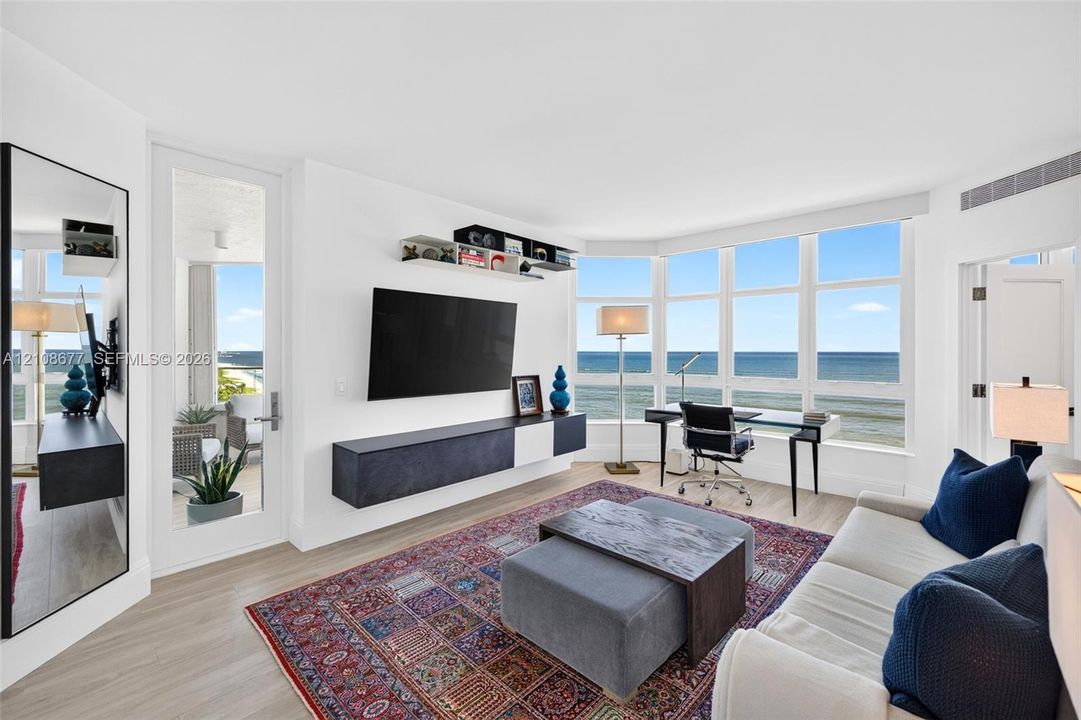 Bedroom / living space featuring expansive floor-to-ceiling windows, wood look plank porcelain flooring, and a wall-mounted floating storage console. Double door entry. Double layered (light filtering and room darkening) remote operated window shades by Bandalux