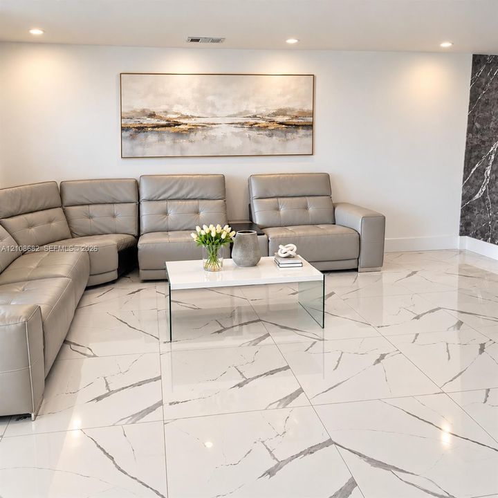 Polished large-format floor tiles featuring a white base with dark veining, recessed ceiling lighting, and a dark stone-finish accent wall