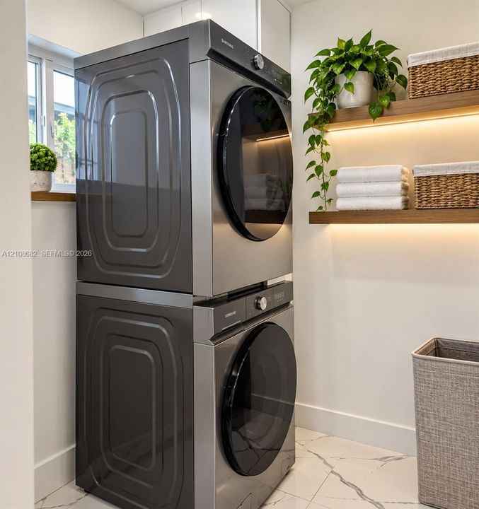 Stacked stainless steel laundry appliances, floating wooden wall shelves with integrated lighting, and white flooring with dark veining