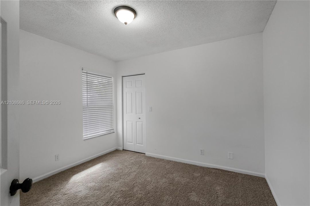 Neutral-toned wall-to-wall carpeting, window with integrated blinds, and multi-panel interior door