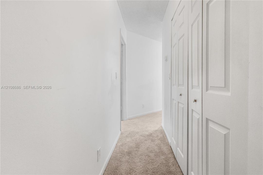 Hallway featuring wall-to-wall carpeting and bi-fold closet doors