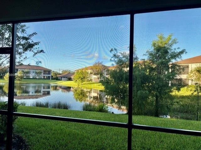 Screened enclosure featuring a pond, grassy grounds, and mature trees