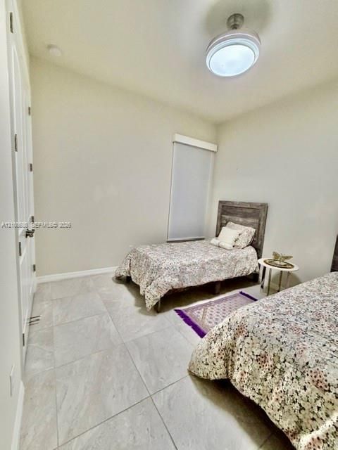 Large-format tile flooring, high ceilings, ceiling-mounted light fixture with fan, and a neutral wall finish