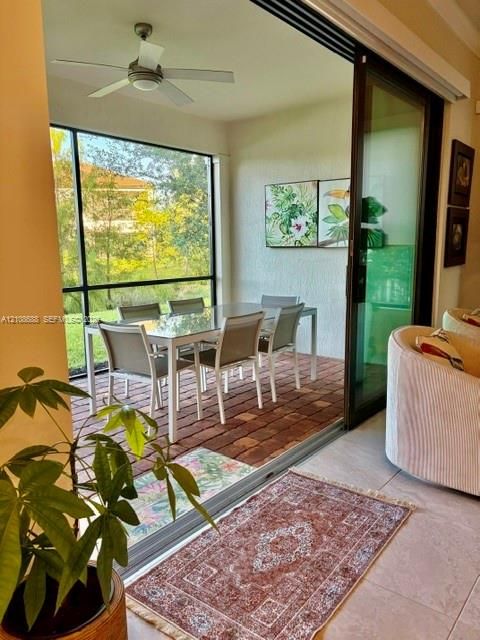 Screened lanai featuring brick paver flooring, a ceiling fan, and large-format sliding glass doors