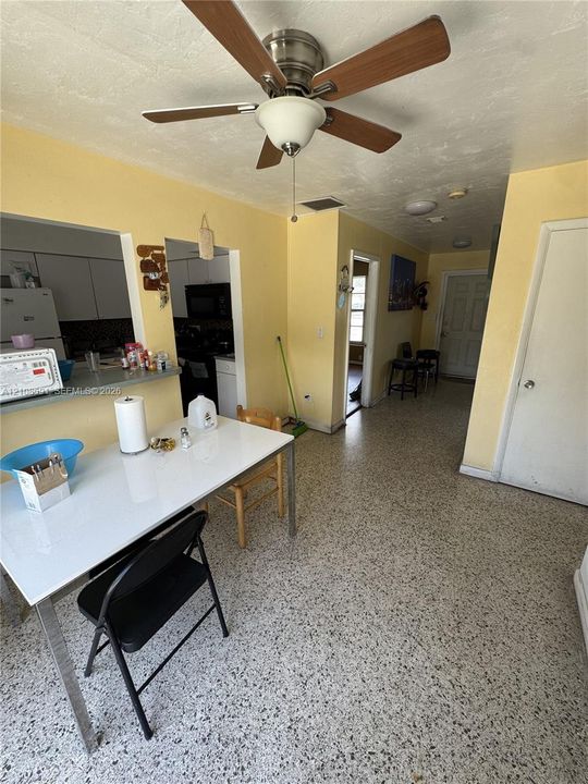 Terrazzo flooring, ceiling fan with integrated lighting, pass-through opening to kitchen, and interior doors