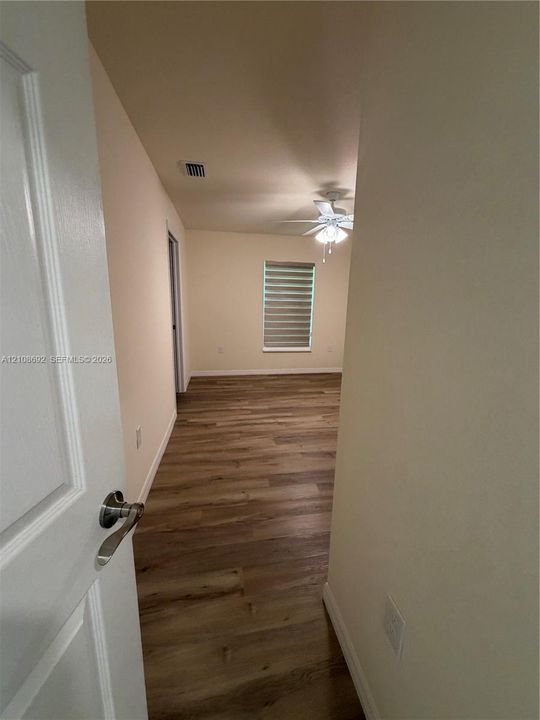 Room featuring wood-finish flooring, a ceiling fan with integrated lighting, and a window with horizontal shades