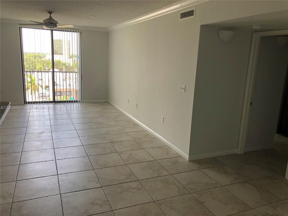 Neutral-toned tile flooring, floor-to-ceiling glass sliding doors, ceiling fan with integrated lighting, and wall-mounted sconce fixtures