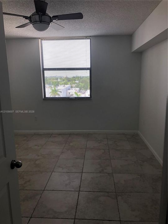 Neutral-toned tile flooring, multi-light ceiling fan, and large picture window