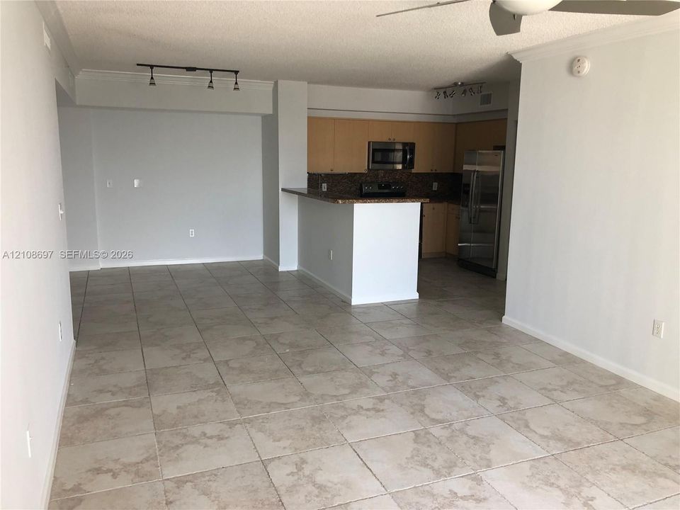 Open-concept interior featuring large-format tile flooring, flat-panel cabinetry, stone countertops, stainless steel appliances, and track lighting