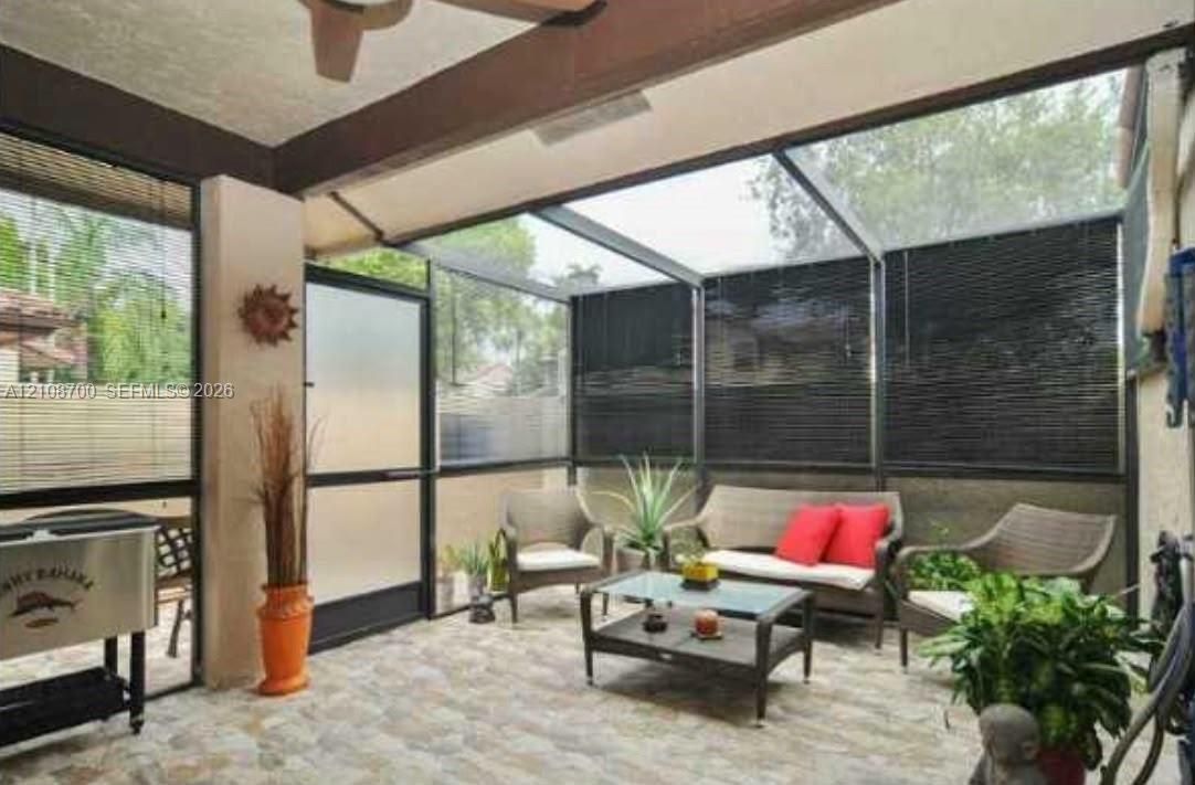 Enclosed patio featuring a screen-in system, tiled flooring, exposed ceiling beams, and a ceiling fan