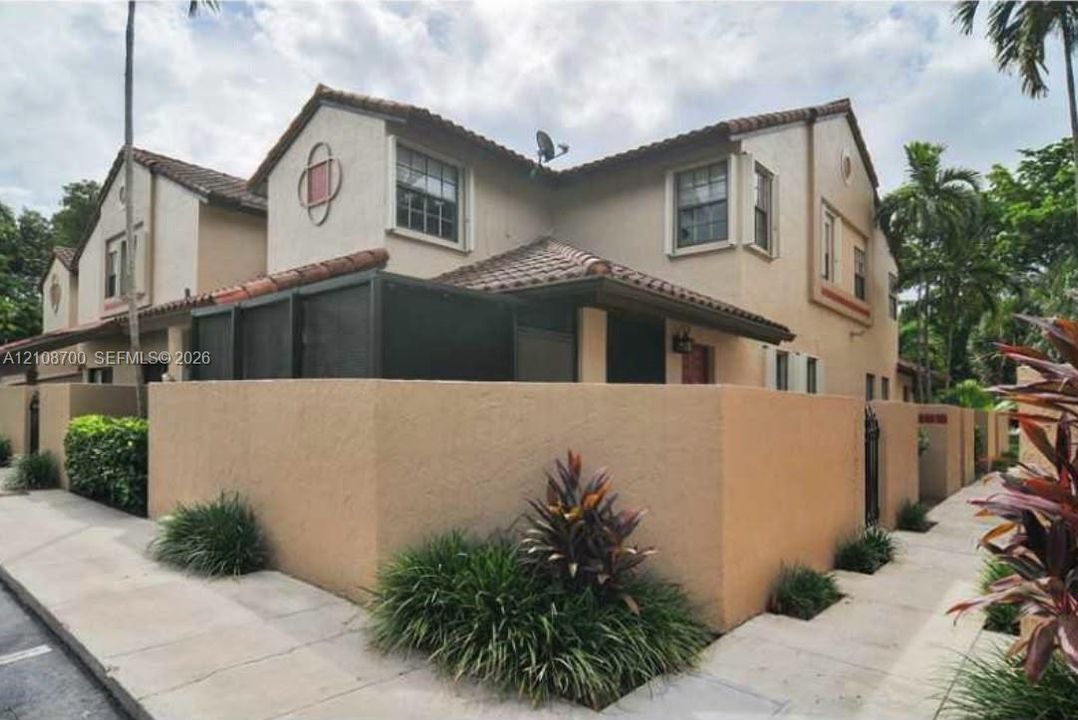 Stucco exterior featuring a clay tile roof, screened-in patio, and privacy wall
