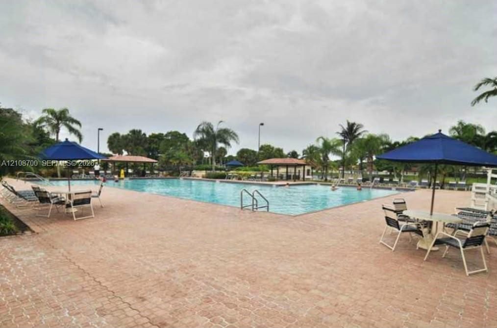 Swimming pool with paver decking, integrated metal pool ladders, and multiple covered pavilions