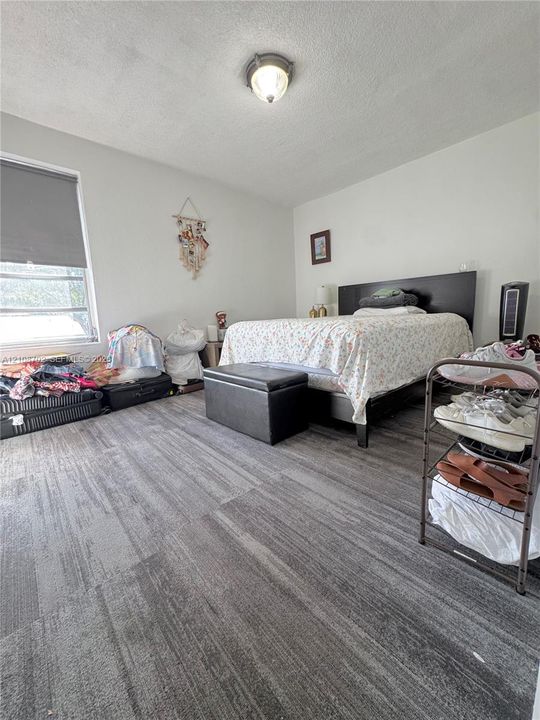 Neutral-toned interior space featuring wood-finish flooring, a single-pane window with a roller shade, and a flush-mount dome ceiling light fixture