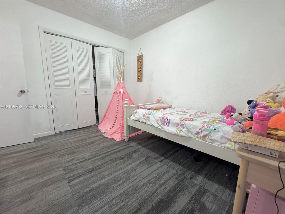 Room featuring wood-finish flooring and a closet with white louvered bi-fold doors