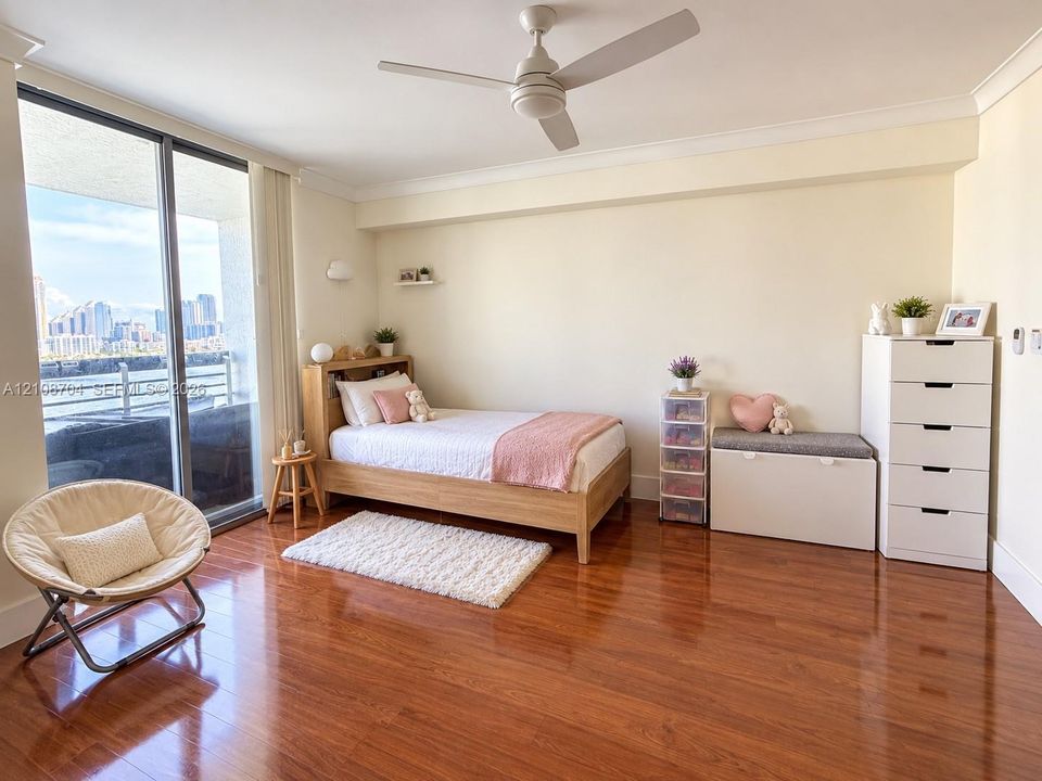 Hardwood flooring, ceiling fan with integrated lighting, and floor-to-ceiling sliding glass doors opening to an exterior balcony