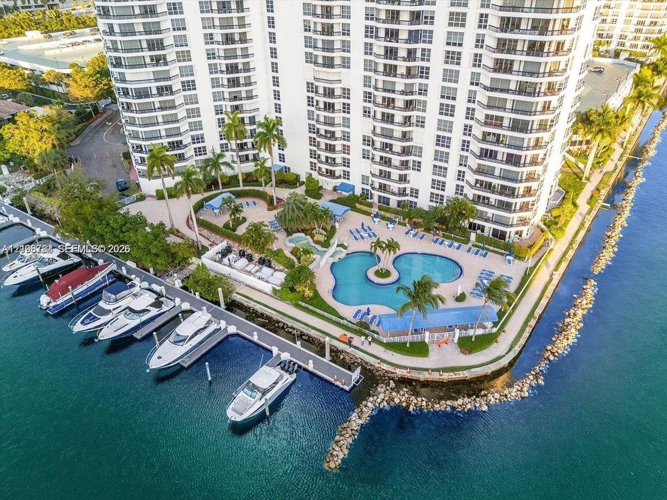 High-rise waterfront property featuring a private boat dock, resort-style swimming pool, paved sundeck, and landscaped grounds