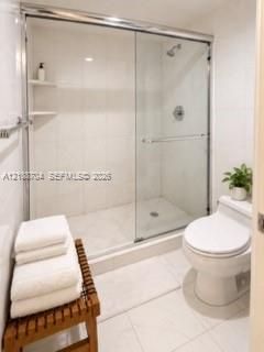 Walk-in shower featuring sliding glass doors, chrome hardware, integrated tile shelving, and tile flooring