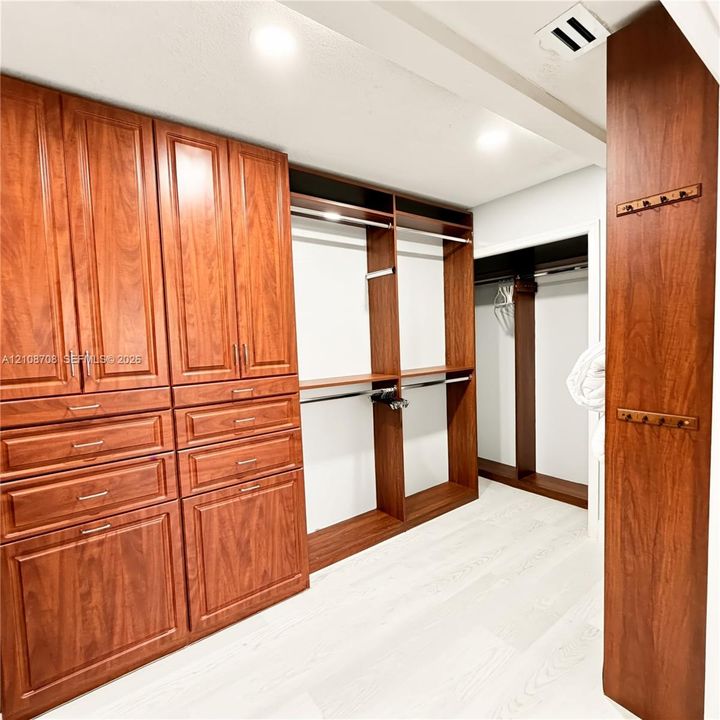 Primary walk in closet with custom built ins