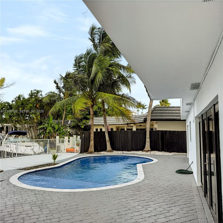 Pool and paver patio with boats along the canal behind