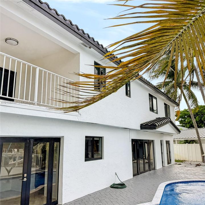 Two story white home with upper balcony and pool