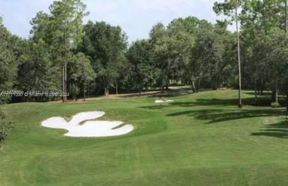 Expansive grounds featuring a manicured fairway, sand bunkers, and mature perimeter trees