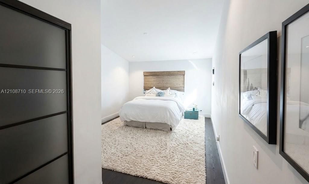 Dark-toned wood-finish flooring, recessed ceiling lighting, and sliding door with frosted glass panels