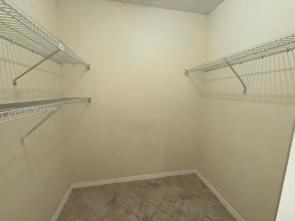 Storage area featuring neutral-toned tile flooring and wall-mounted wire shelving units
