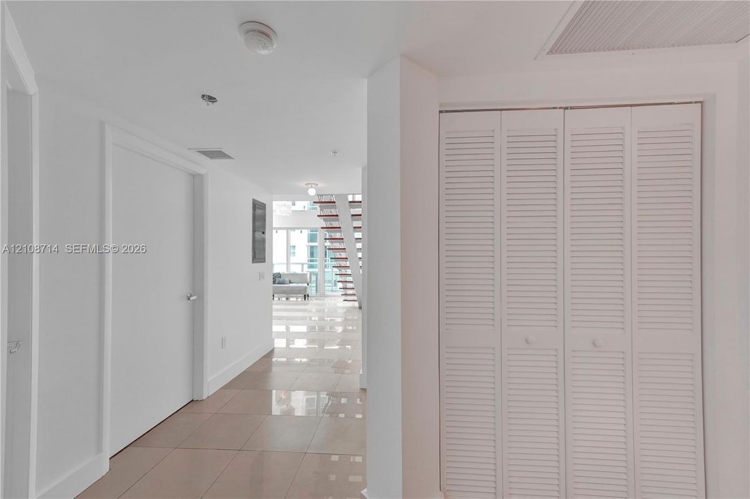 Glossy tile flooring, louvered bi-fold closet doors, and a staircase with open risers