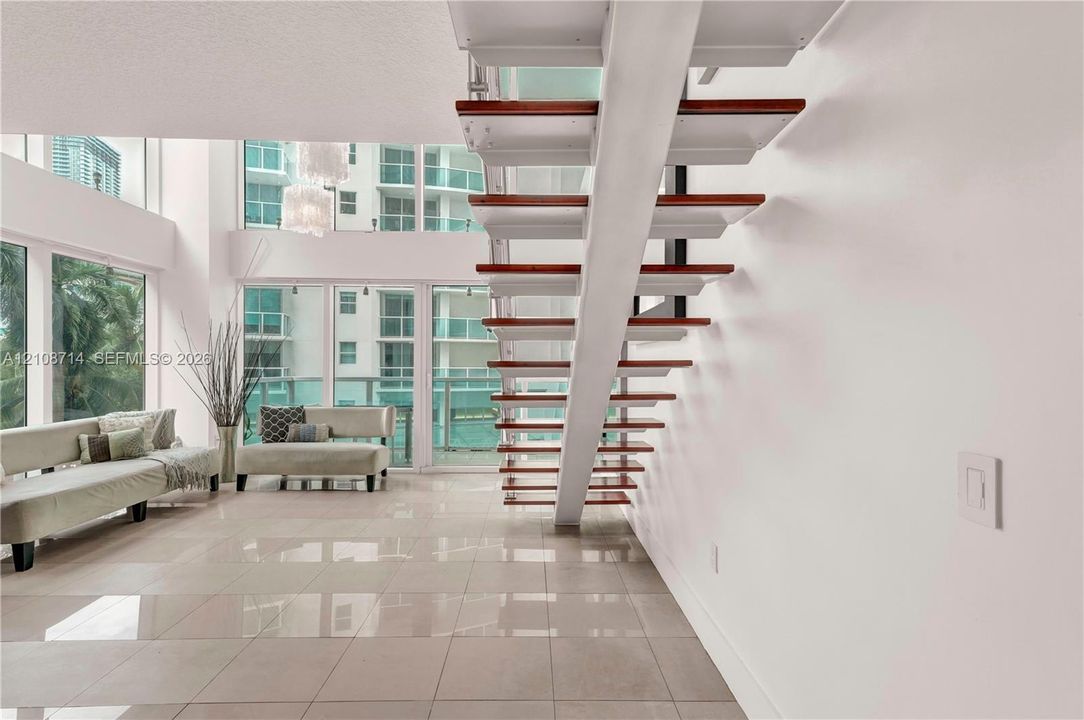 Floating staircase featuring wood treads and white stringers, floor-to-ceiling windows, and tile flooring