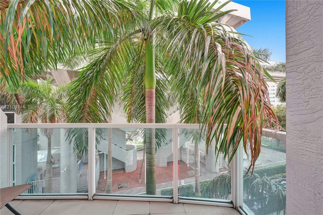 Covered balcony featuring tile flooring and a glass-paneled railing