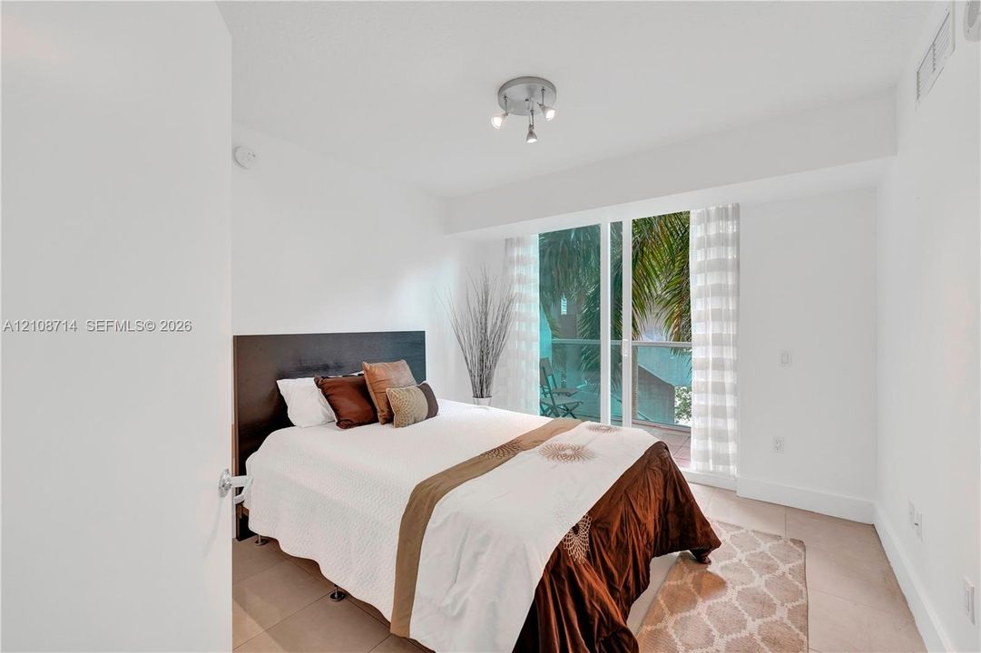 Floor-to-ceiling glass sliding doors, neutral tile flooring, and multi-directional ceiling-mounted lighting