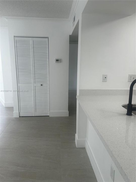 Neutral-toned tile flooring, quartz countertops, matte black faucet, and white louvered-door closet