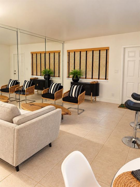 Interior space featuring expansive wall-to-wall mirror panels, large-format tile flooring, and integrated window blinds with textured fabric detail