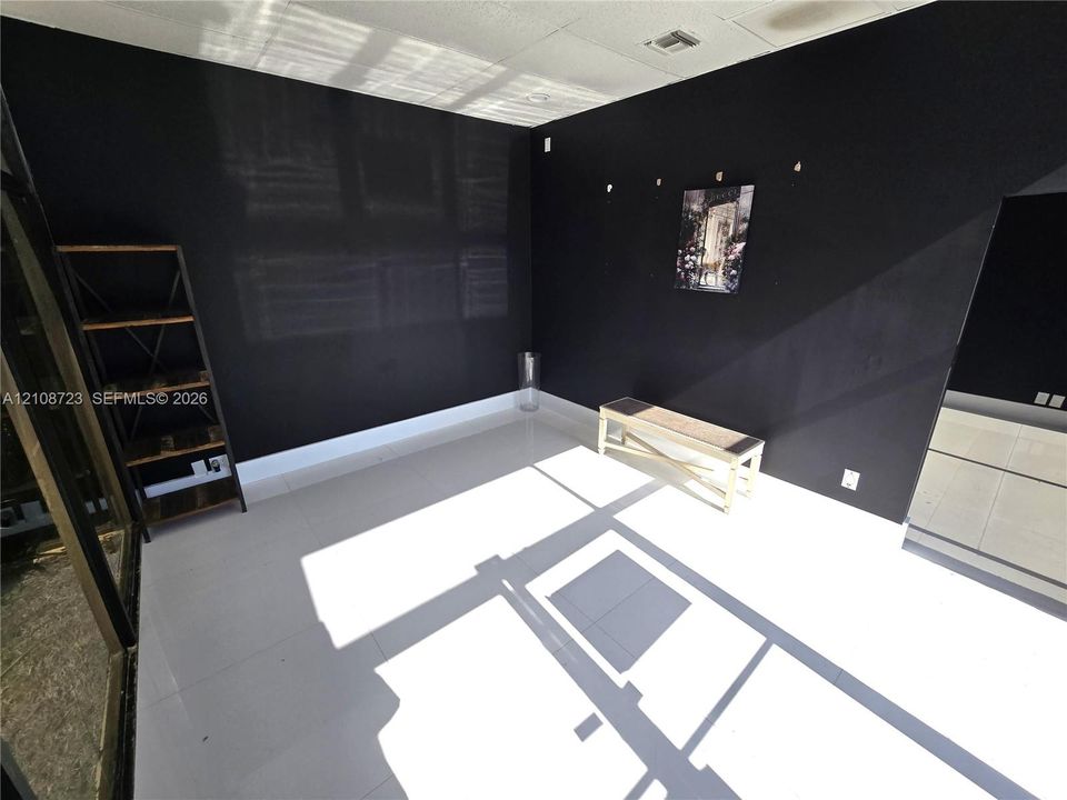 Interior room featuring matte black wall paint, large format tile flooring, and a glass-paneled sliding door