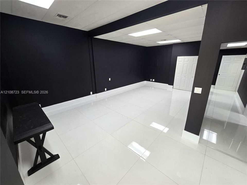 Interior space featuring high-gloss tile flooring, bold monochromatic wall finishes, recessed ceiling lighting, and double-panel doors