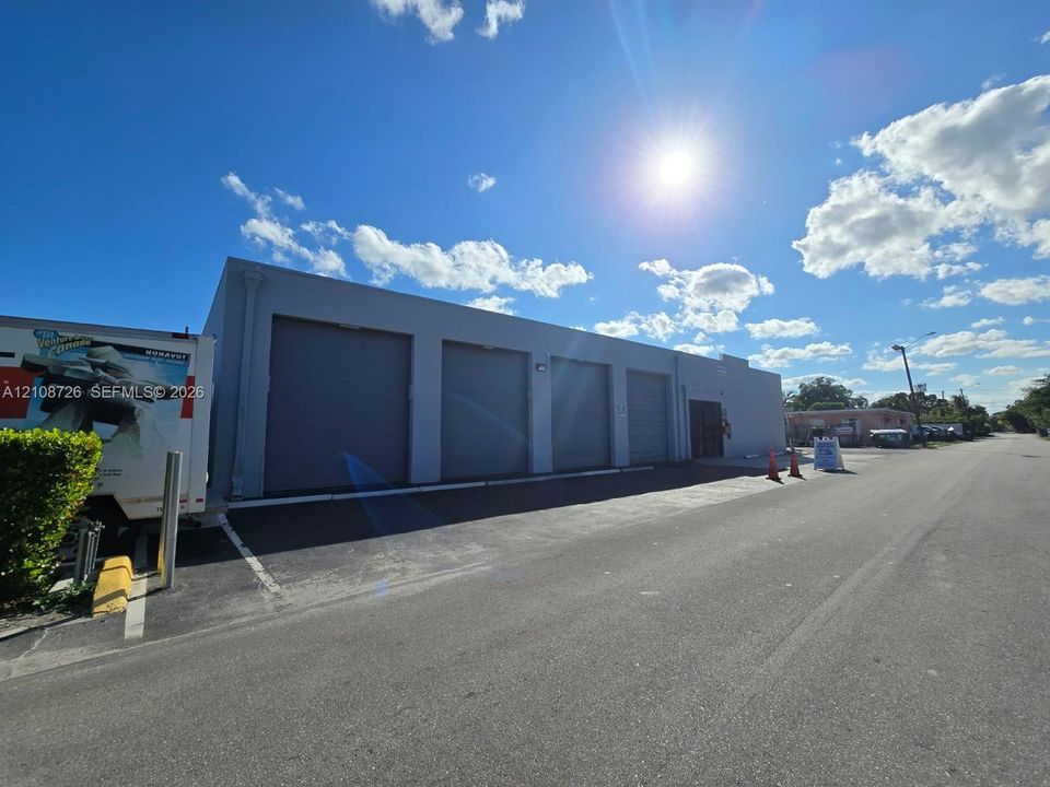 Industrial exterior featuring four roll-up bay doors and asphalt paving