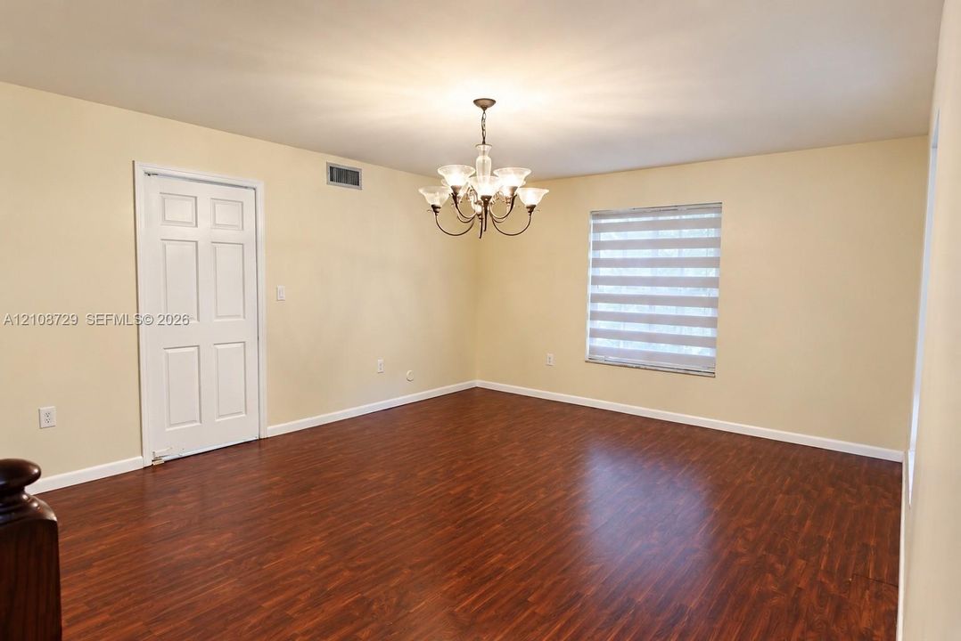 Wood laminated flooring, multi-light chandelier,  interior door with access to the kitchen