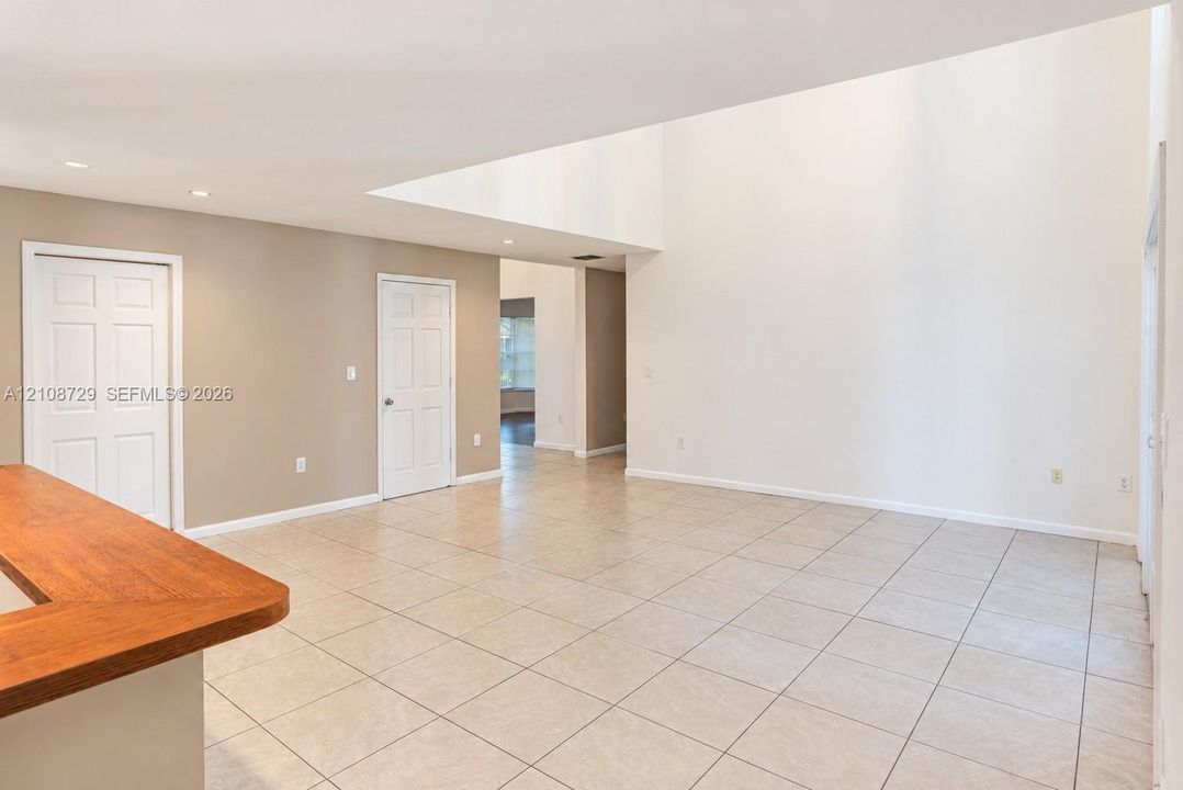 Interior featuring high vaulted ceilings, light-colored ceramic tile flooring, two-panel interior doors, and a built-in wooden counter surface