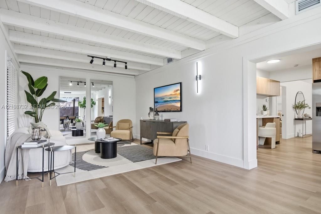 Exposed beam ceiling with white finish, light-toned wood-finish flooring, dual floor-to-ceiling wall mirrors, track lighting, and linear wall-mounted light fixture