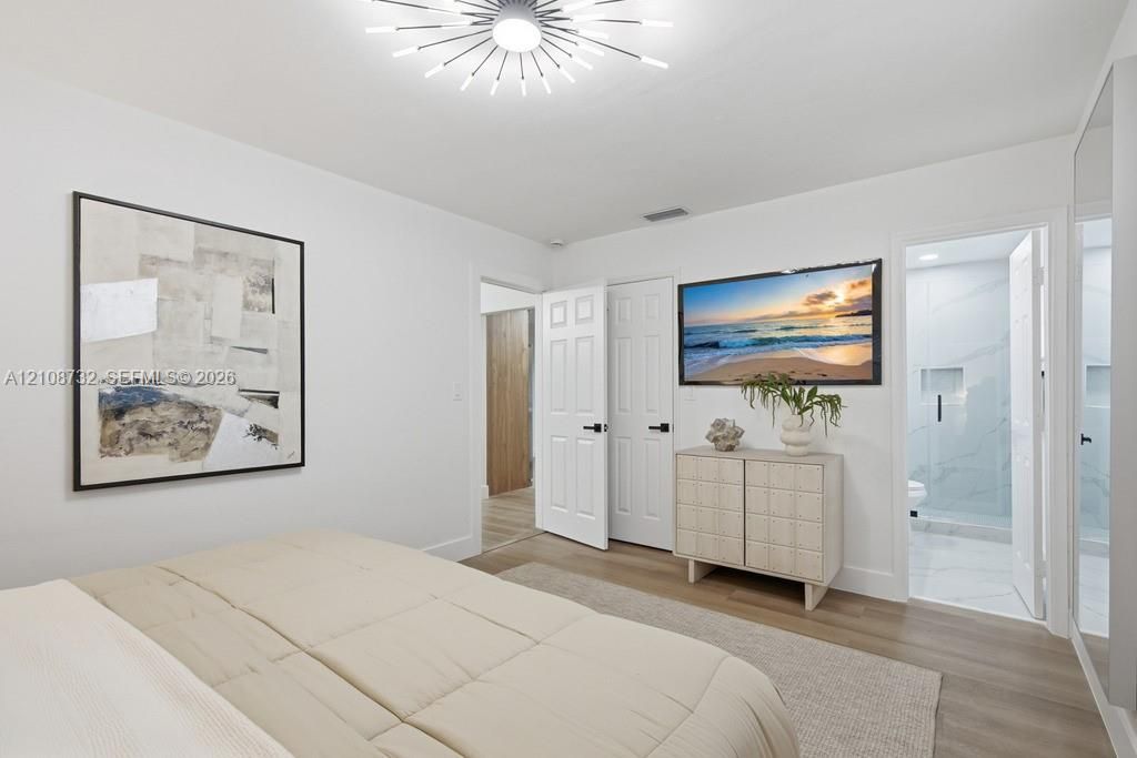 Multi-panel six-door interior doors with matte black hardware, wood-finish flooring, and contemporary sunburst-style ceiling light fixture