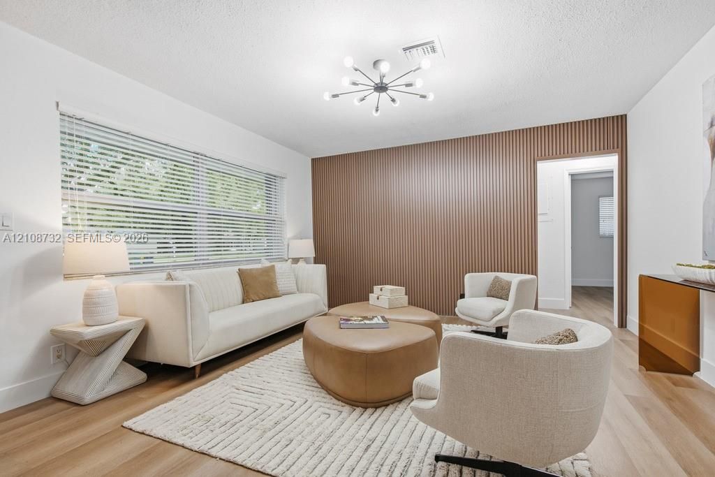 Living space featuring wood-finish flooring, a decorative vertical-slat accent wall, and a multi-bulb sputnik-style light fixture