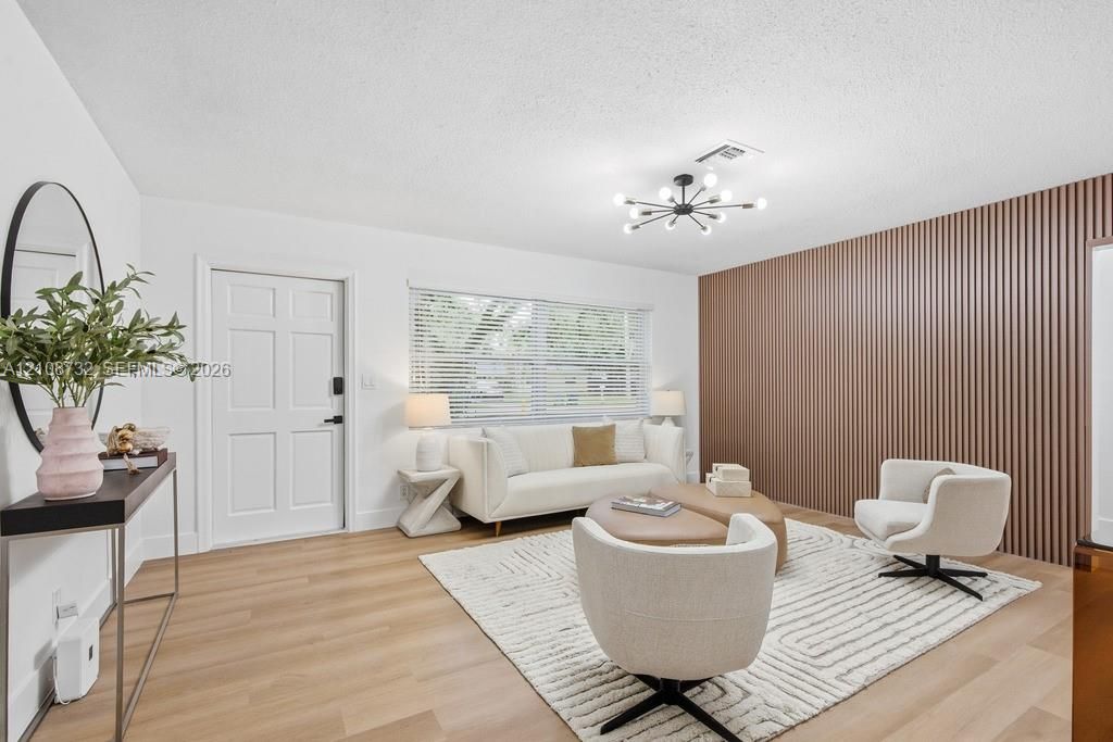 Interior space featuring wood-finish flooring, a decorative vertical slat accent wall, and a multi-arm sputnik chandelier