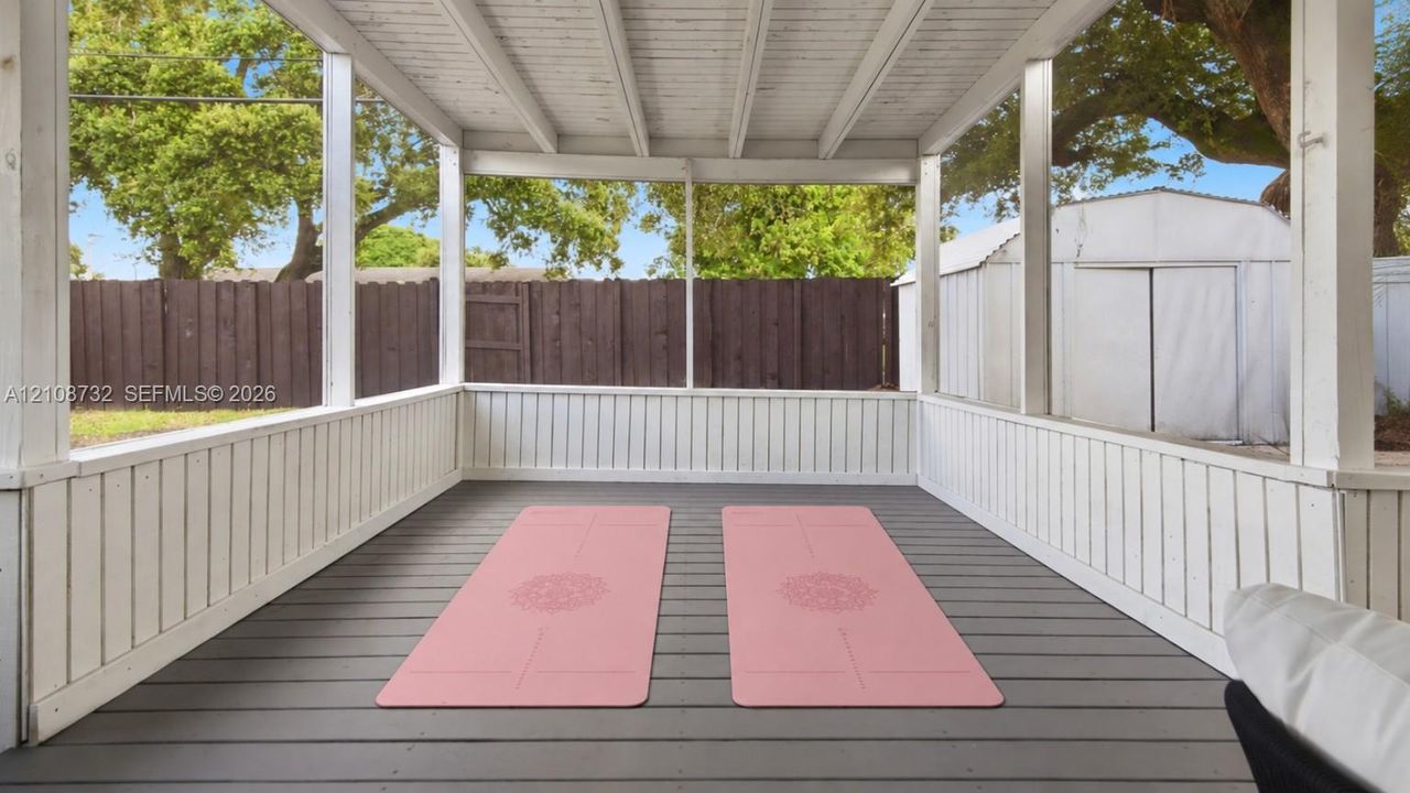 Screened porch featuring painted wood railings, a composite floor, and an exposed beamed ceiling